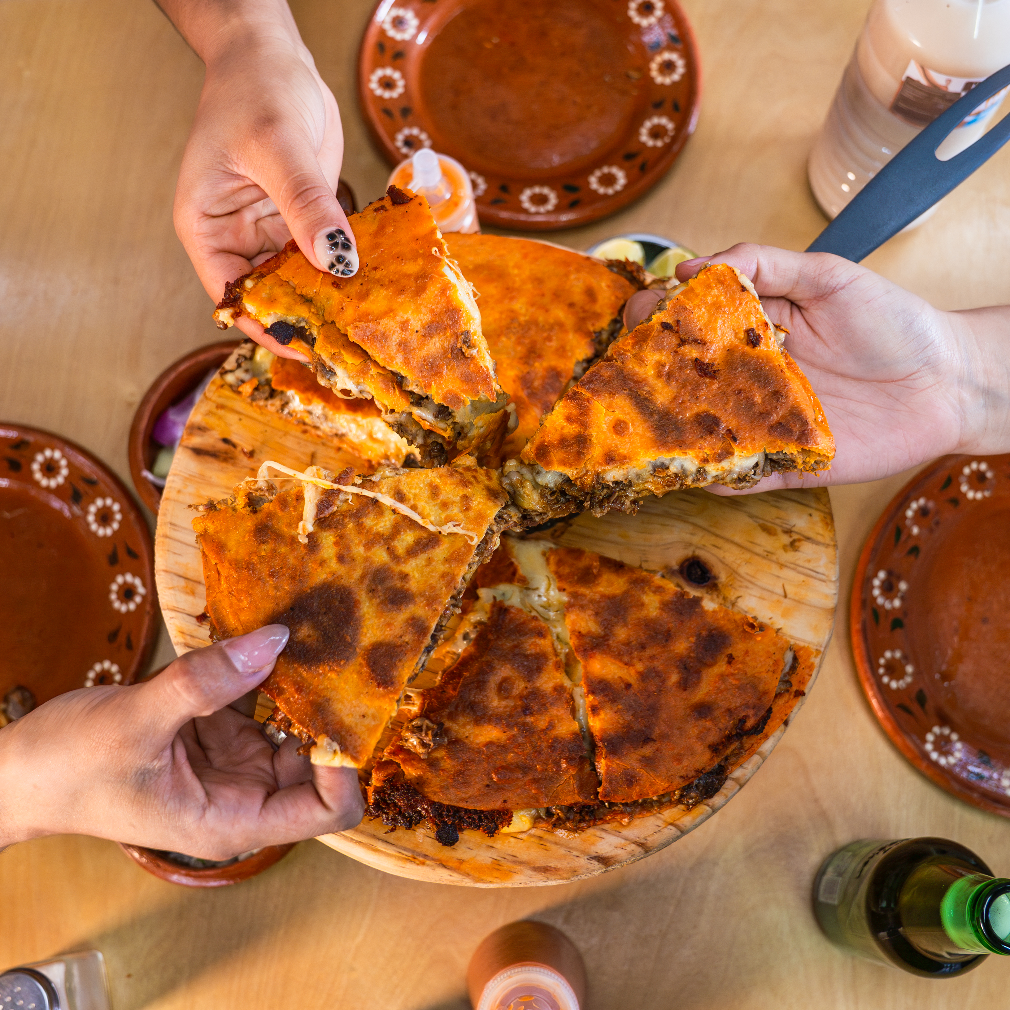 Pizzadilla de birria recién cortada, con el queso derritiéndose entre las rebanadas