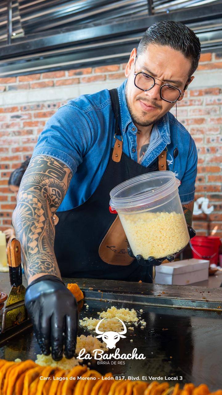Chef de La Barbacha espolvoreando queso sobre la plancha, preparando un platillo con la receta familiar