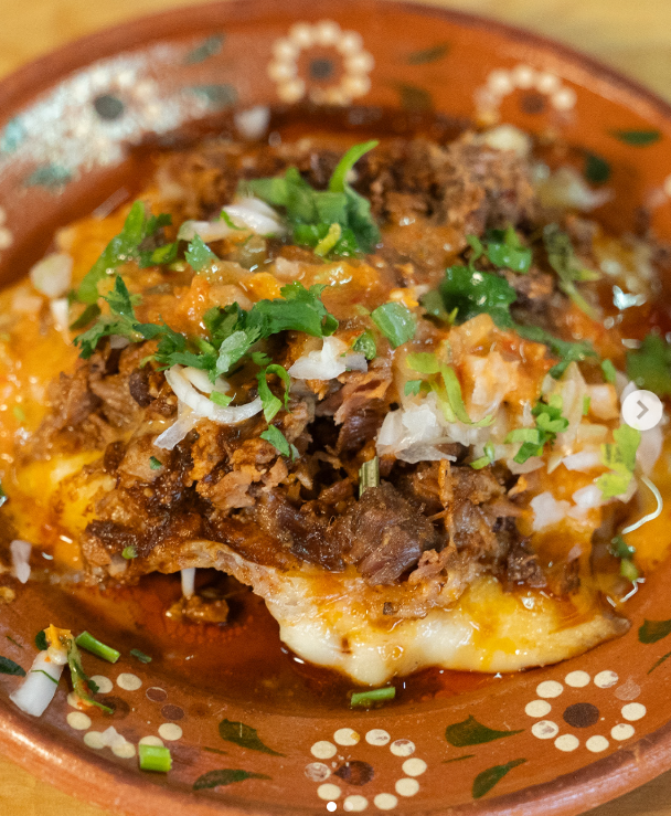 Chorreada: base de queso derretido cubierta con birria deshebrada, cebolla y cilantro picados
