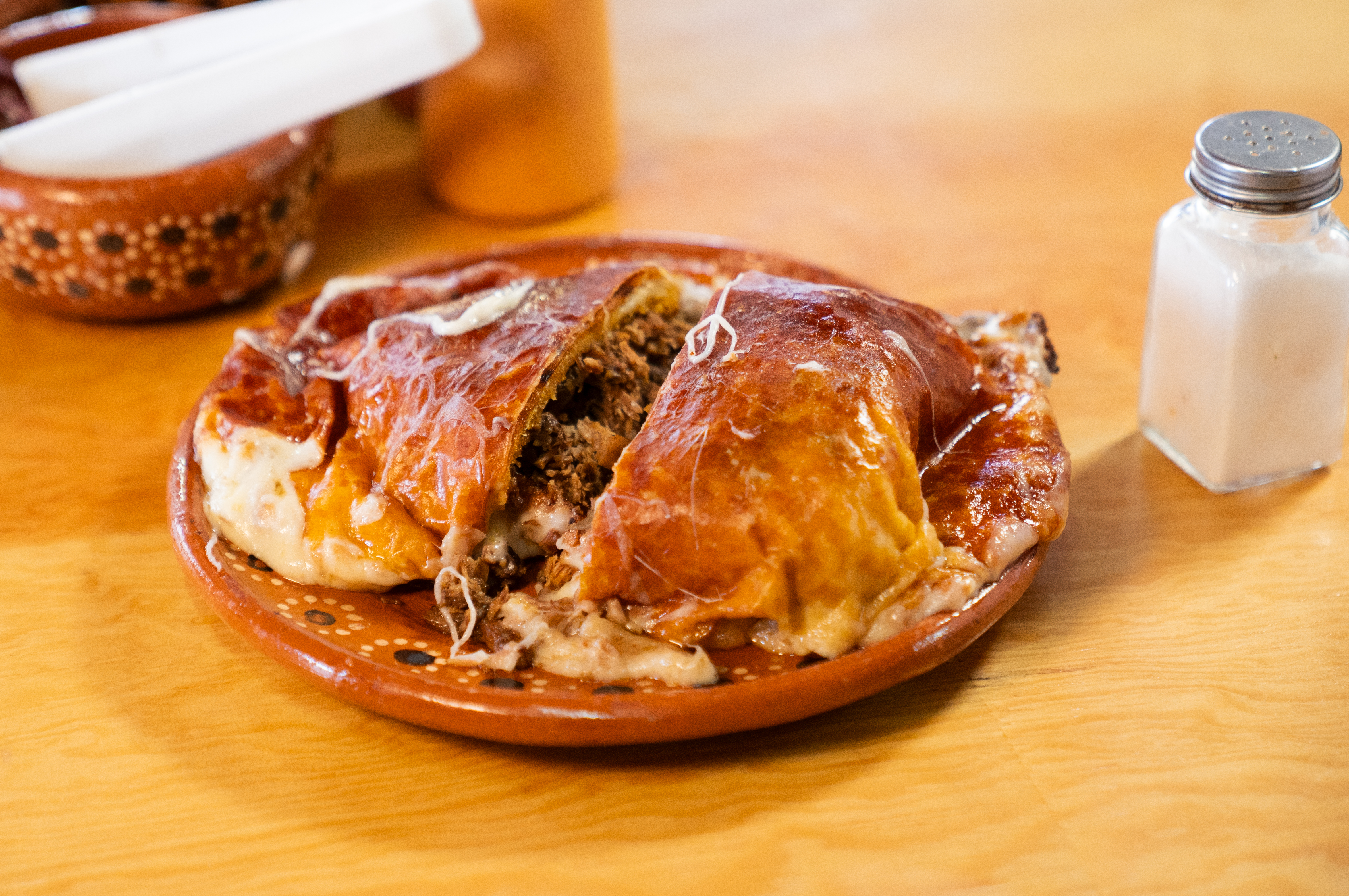 Momia cortada a la mitad, mostrando el relleno de birria y queso derretido